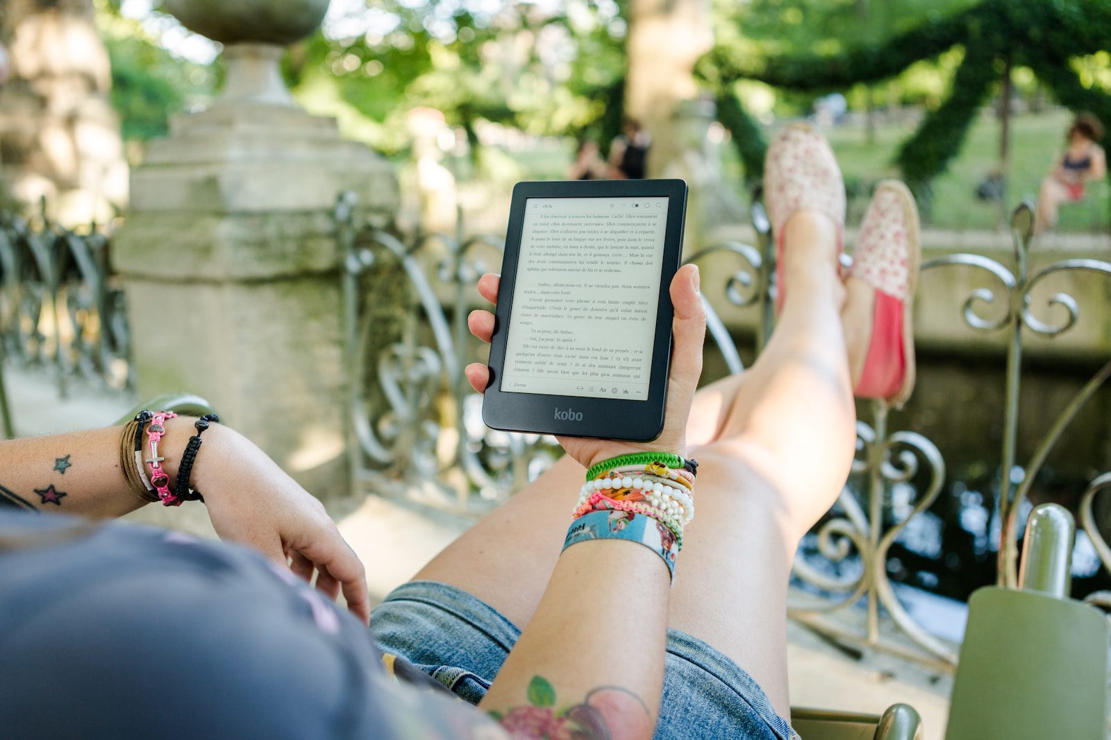 woman lying on chair holding ebook reader